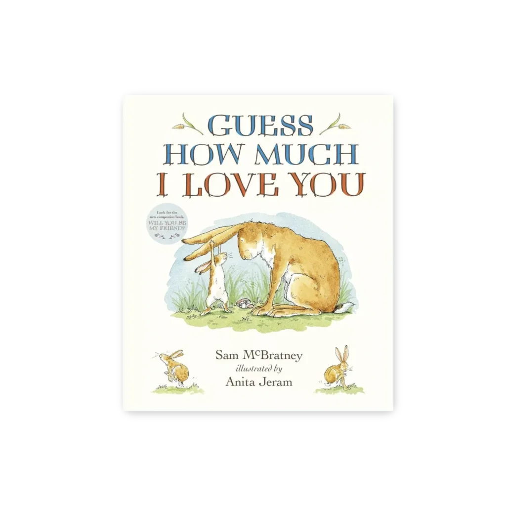 Okładka książki „Guess How Much I Love You” z ilustracją Małego i Dużego Brązowego Zajączka siedzących na trawie na tle pastelowego nieba