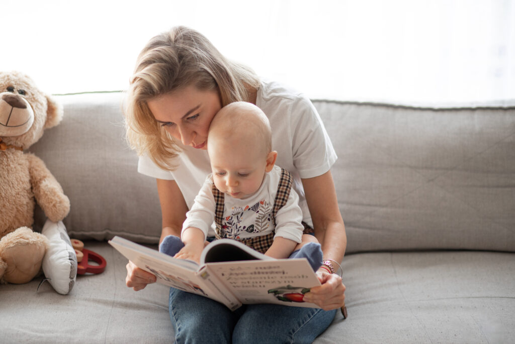 Ilustracja przedstawiająca mamę z niemowlakiem trzymającymi książkę, symbolizująca wspólne czytanie książek w języku angielskim
