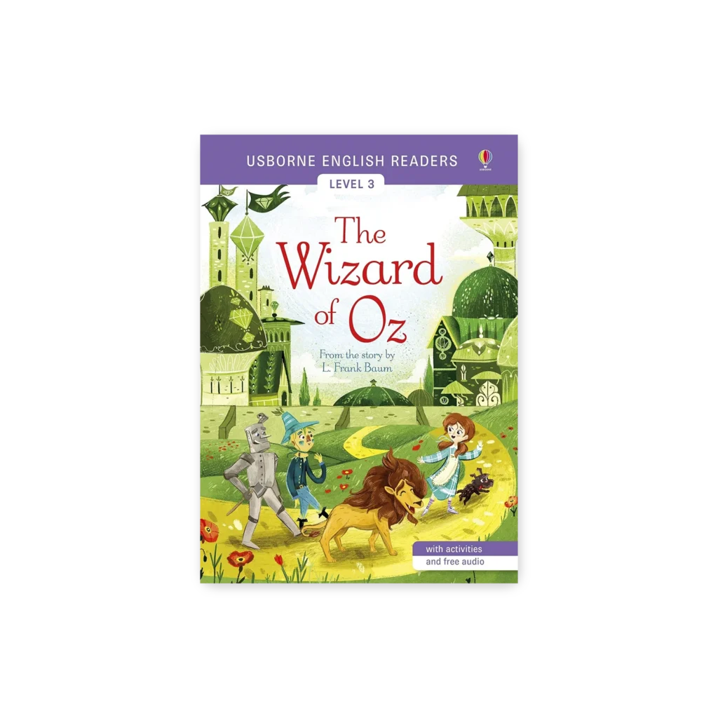 Okładka książki „The Wizard of Oz” z ilustracją Dorotki, Lwa, Drwala i Stracha na Wróble idących żółtą drogą do Szmaragdowego Grodu.